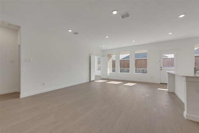 unfurnished living room featuring light wood-style floors, visible vents, and baseboards