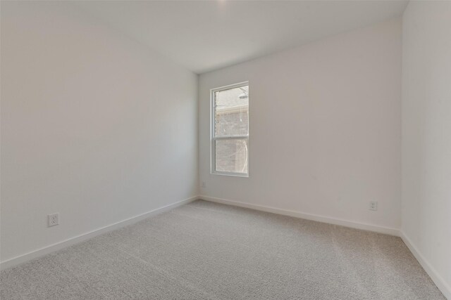 unfurnished room with light colored carpet and baseboards
