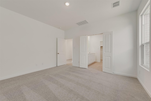 unfurnished bedroom with light carpet, visible vents, and baseboards