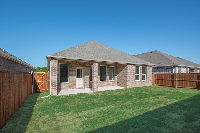 rear view of house featuring a fenced backyard, a lawn, a patio, roof with shingles, and brick siding
