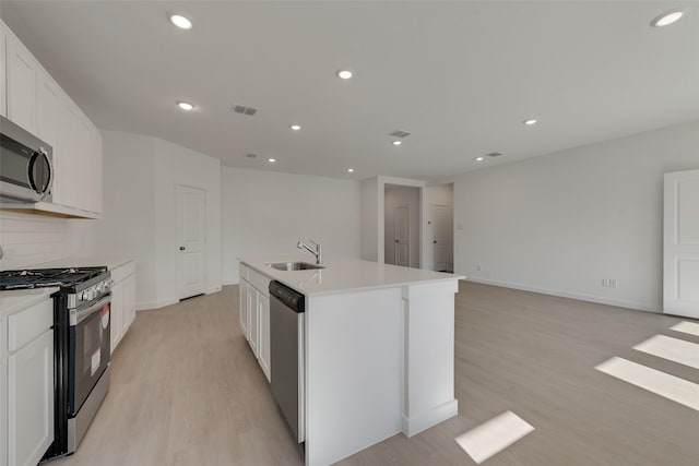 kitchen with light wood-style floors, visible vents, a kitchen island with sink, a sink, and stainless steel appliances