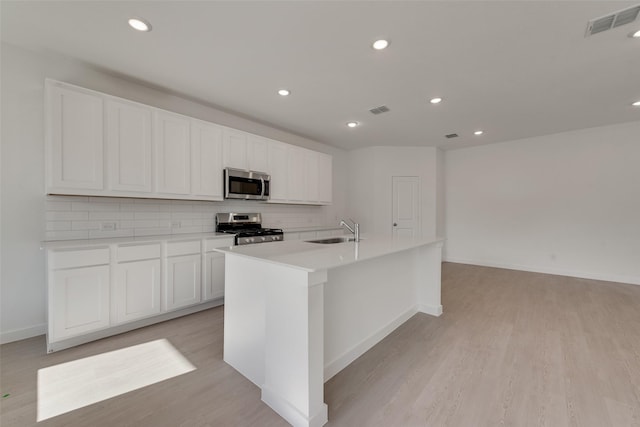 kitchen with light wood-type flooring, visible vents, appliances with stainless steel finishes, a sink, and decorative backsplash
