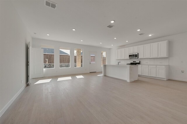 unfurnished living room with visible vents, baseboards, light wood-style floors, and a healthy amount of sunlight