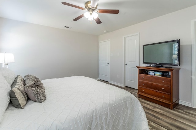 bedroom with a ceiling fan, visible vents, dark wood finished floors, and baseboards