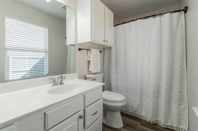 bathroom with toilet, plenty of natural light, wood finished floors, and vanity