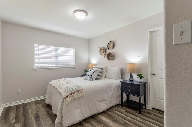 bedroom with baseboards and dark wood-type flooring