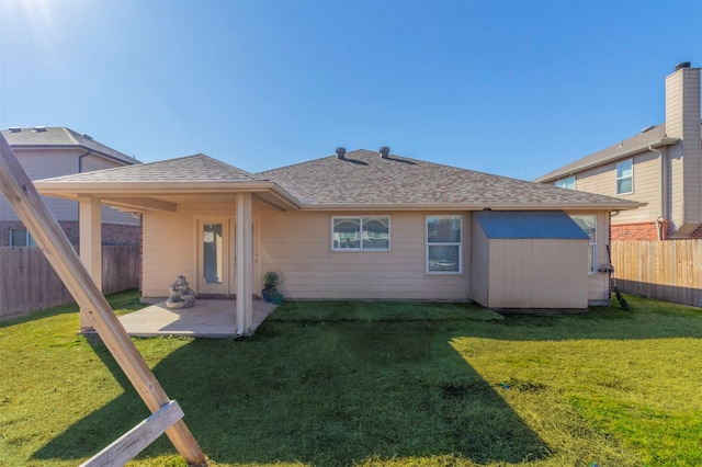 back of house with a yard, a fenced backyard, a shingled roof, and a patio