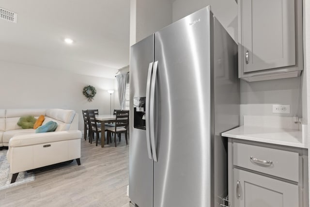 kitchen featuring stainless steel fridge, visible vents, open floor plan, light countertops, and gray cabinetry