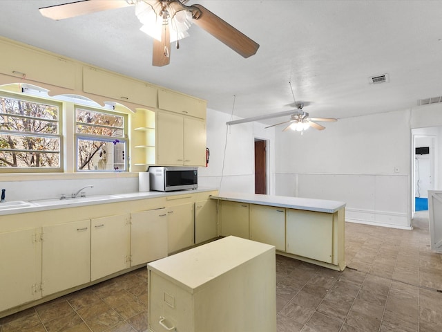 kitchen featuring ceiling fan, sink, a kitchen island, and cream cabinets