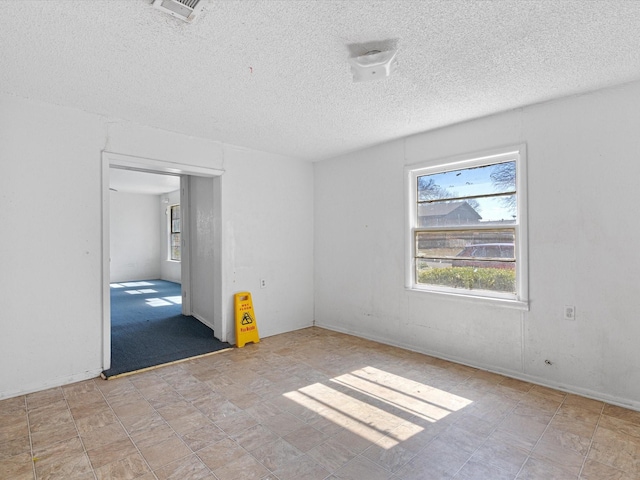 unfurnished room featuring a wealth of natural light and a textured ceiling