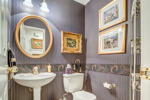 half bath with toilet and wallpapered walls