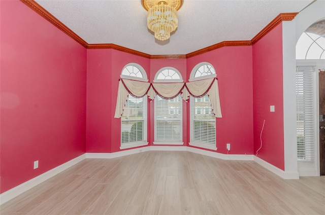 unfurnished room featuring hardwood / wood-style flooring, ornamental molding, an inviting chandelier, and a textured ceiling