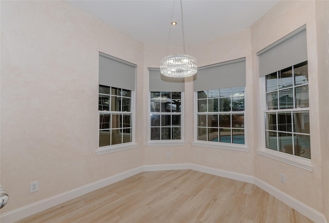 unfurnished dining area featuring a notable chandelier and wood-type flooring