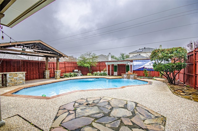 view of swimming pool featuring a patio, an outdoor structure, a gazebo, and pool water feature