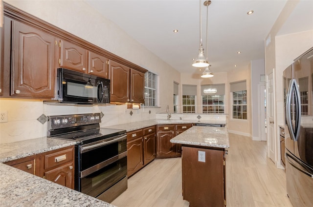 kitchen featuring a center island, backsplash, light stone counters, appliances with stainless steel finishes, and pendant lighting