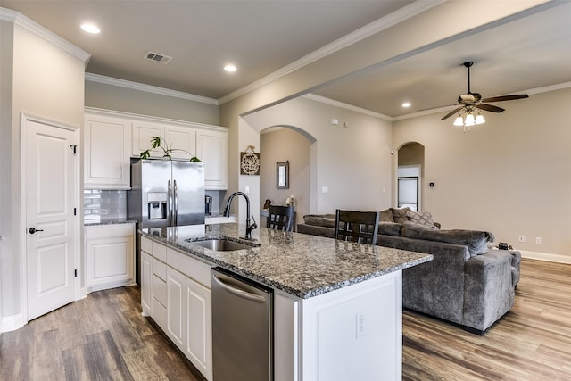 kitchen with a center island with sink, appliances with stainless steel finishes, sink, white cabinets, and hardwood / wood-style flooring