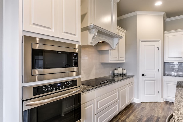 kitchen with stainless steel appliances, white cabinetry, and dark stone countertops