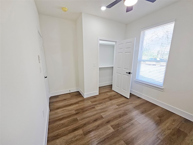 unfurnished bedroom featuring a closet, hardwood / wood-style floors, a walk in closet, and ceiling fan