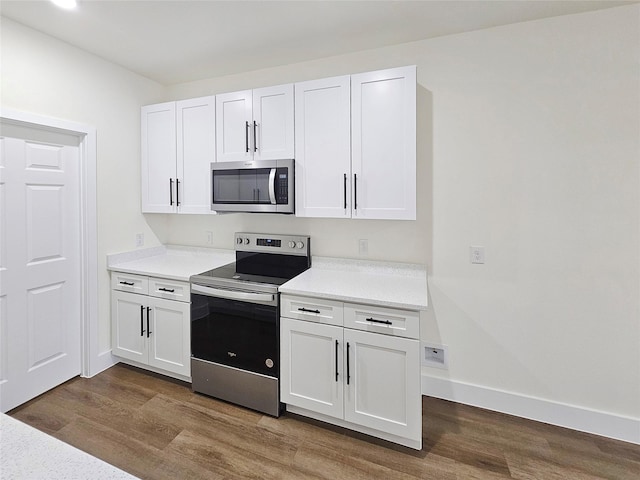 kitchen with stainless steel appliances, white cabinets, and hardwood / wood-style floors