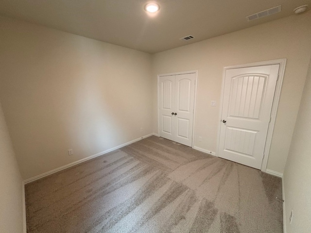 unfurnished bedroom with visible vents, a closet, carpet flooring, and baseboards