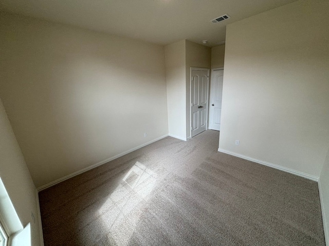 spare room featuring carpet flooring, visible vents, and baseboards
