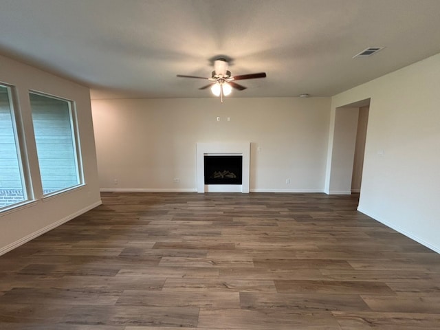 unfurnished living room with a fireplace, wood finished floors, a ceiling fan, and baseboards
