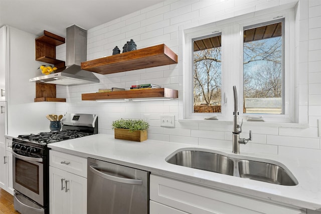 kitchen featuring white cabinets, wall chimney exhaust hood, stainless steel appliances, open shelves, and a sink