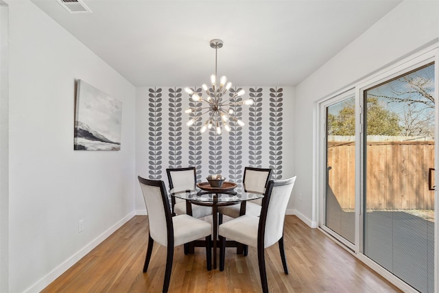 dining space with a notable chandelier, baseboards, visible vents, and wood finished floors