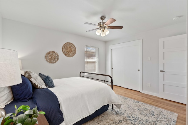 bedroom featuring a closet, wood finished floors, a ceiling fan, and baseboards