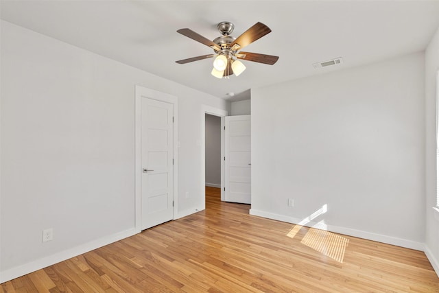 spare room with ceiling fan, light wood finished floors, visible vents, and baseboards