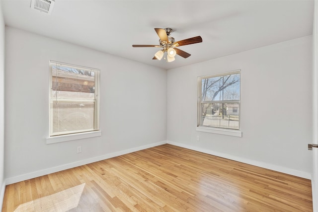 unfurnished room featuring a ceiling fan, visible vents, baseboards, and wood finished floors