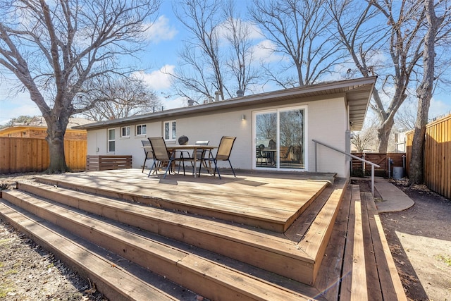 wooden terrace featuring outdoor dining area and a fenced backyard