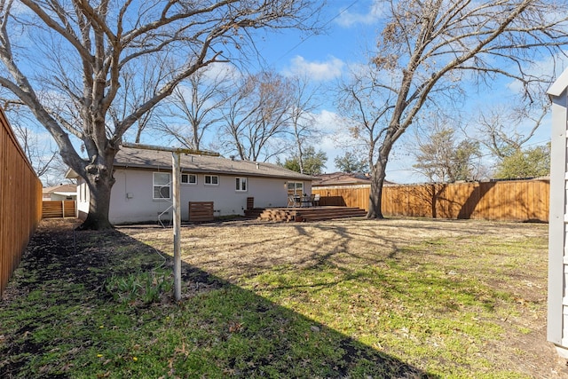 back of property with a fenced backyard, a lawn, and a wooden deck