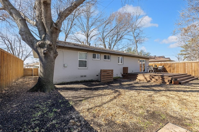 rear view of house featuring a deck, brick siding, crawl space, and a fenced backyard