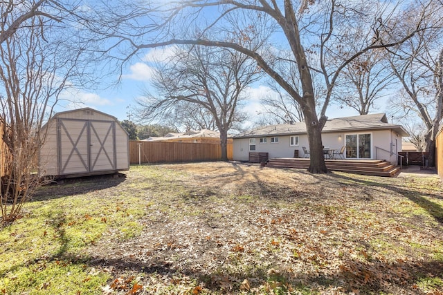 view of yard with a storage shed, an outbuilding, a fenced backyard, and a wooden deck