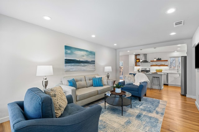 living room with light wood-style floors, recessed lighting, visible vents, and baseboards