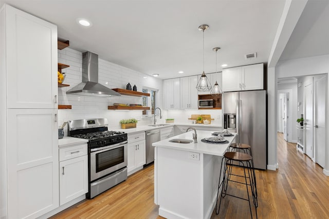 kitchen featuring white cabinets, light countertops, appliances with stainless steel finishes, wall chimney exhaust hood, and open shelves