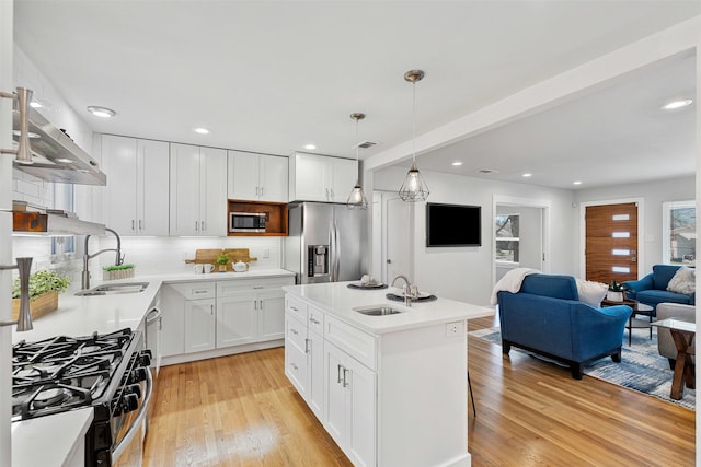 kitchen featuring stainless steel appliances, white cabinetry, open floor plan, light countertops, and decorative light fixtures