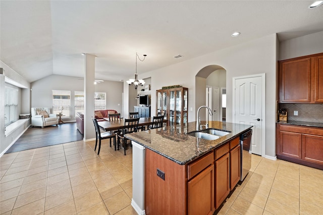 kitchen featuring light tile patterned floors, sink, a kitchen island with sink, and dark stone countertops