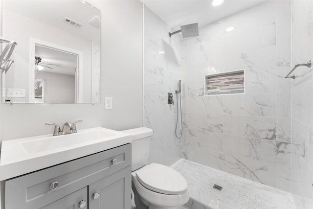 full bath featuring toilet, tiled shower, vanity, and visible vents