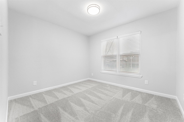 unfurnished room featuring carpet and baseboards