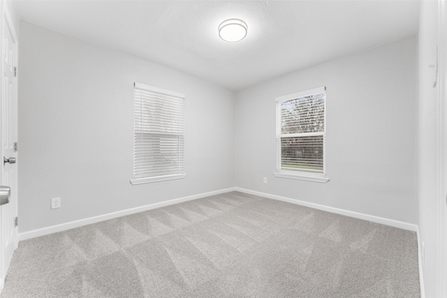 spare room with light carpet and baseboards