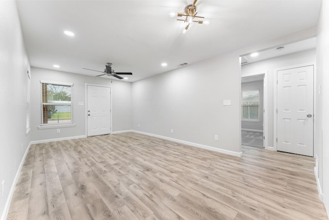 empty room featuring light wood-style floors, recessed lighting, baseboards, and ceiling fan with notable chandelier