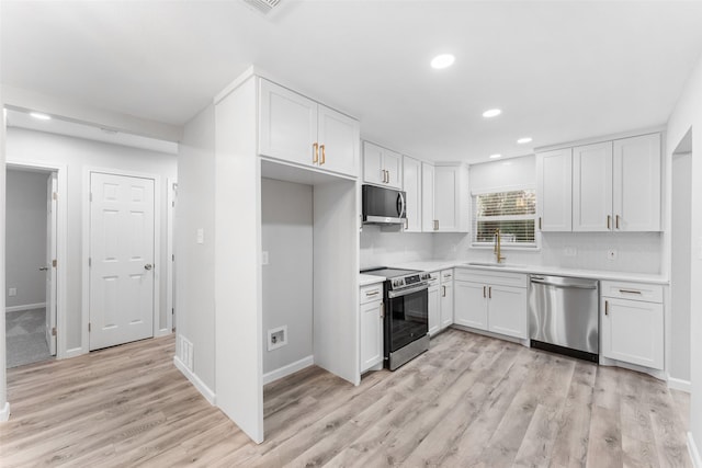 kitchen featuring stainless steel appliances, a sink, white cabinetry, light countertops, and light wood-type flooring