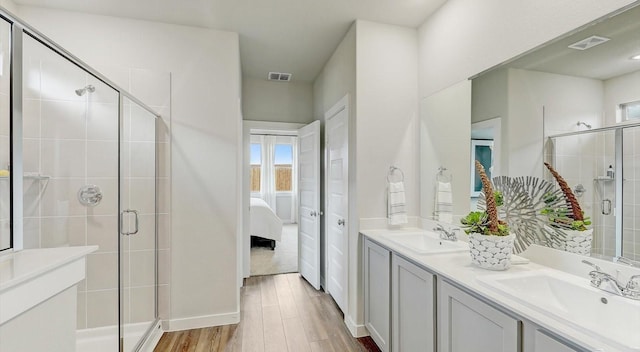 bathroom with hardwood / wood-style floors, a shower with shower door, and vanity