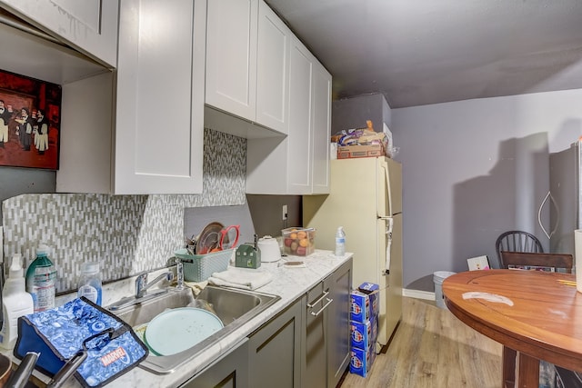 kitchen featuring light hardwood / wood-style flooring, decorative backsplash, white refrigerator, sink, and white cabinetry