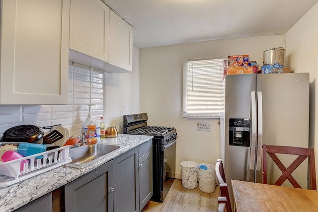 kitchen with white cabinets, gas stove, stainless steel fridge, gray cabinets, and sink