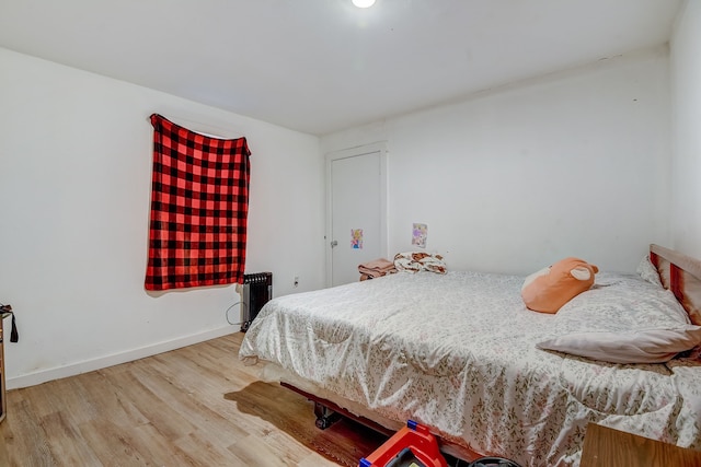 bedroom with radiator heating unit and hardwood / wood-style floors