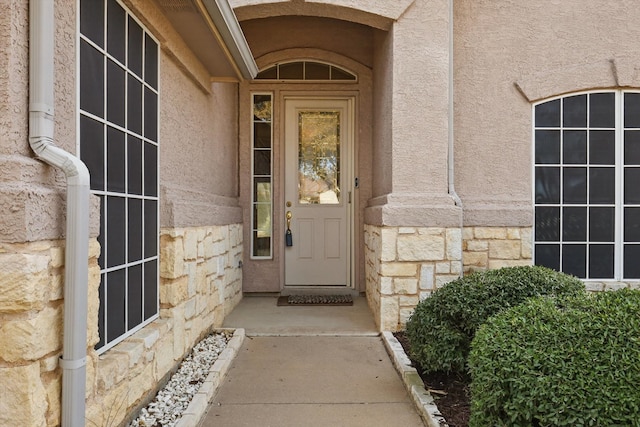 property entrance featuring stone siding and stucco siding