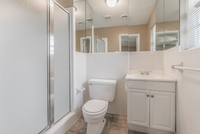 bathroom with toilet, tile walls, a shower with shower door, and vanity